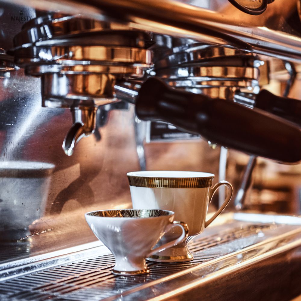 Copper commercial espresso machine group heads with gold-rimmed cups